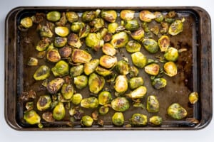 Overhead view of a baking sheet with freshly baked brussel sprouts halved that are brown and crisp.