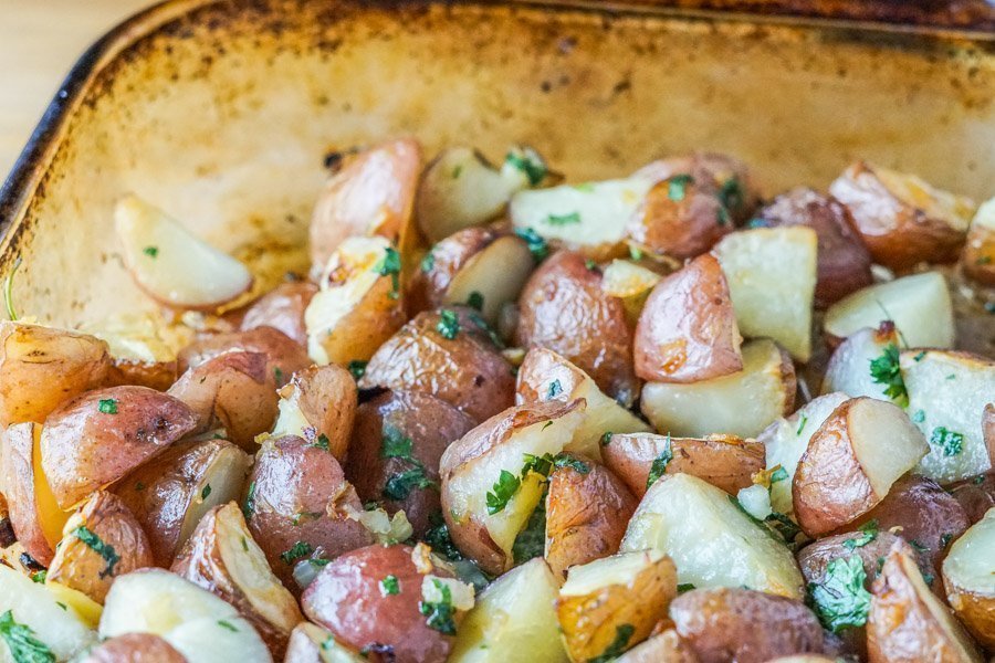 A side and close-up view of crispy roasted red skin potatoes with parsley.