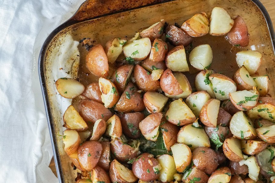 Overhead view of a large glass baking dish with crispy roasted parsley potatoes, ready to serve!