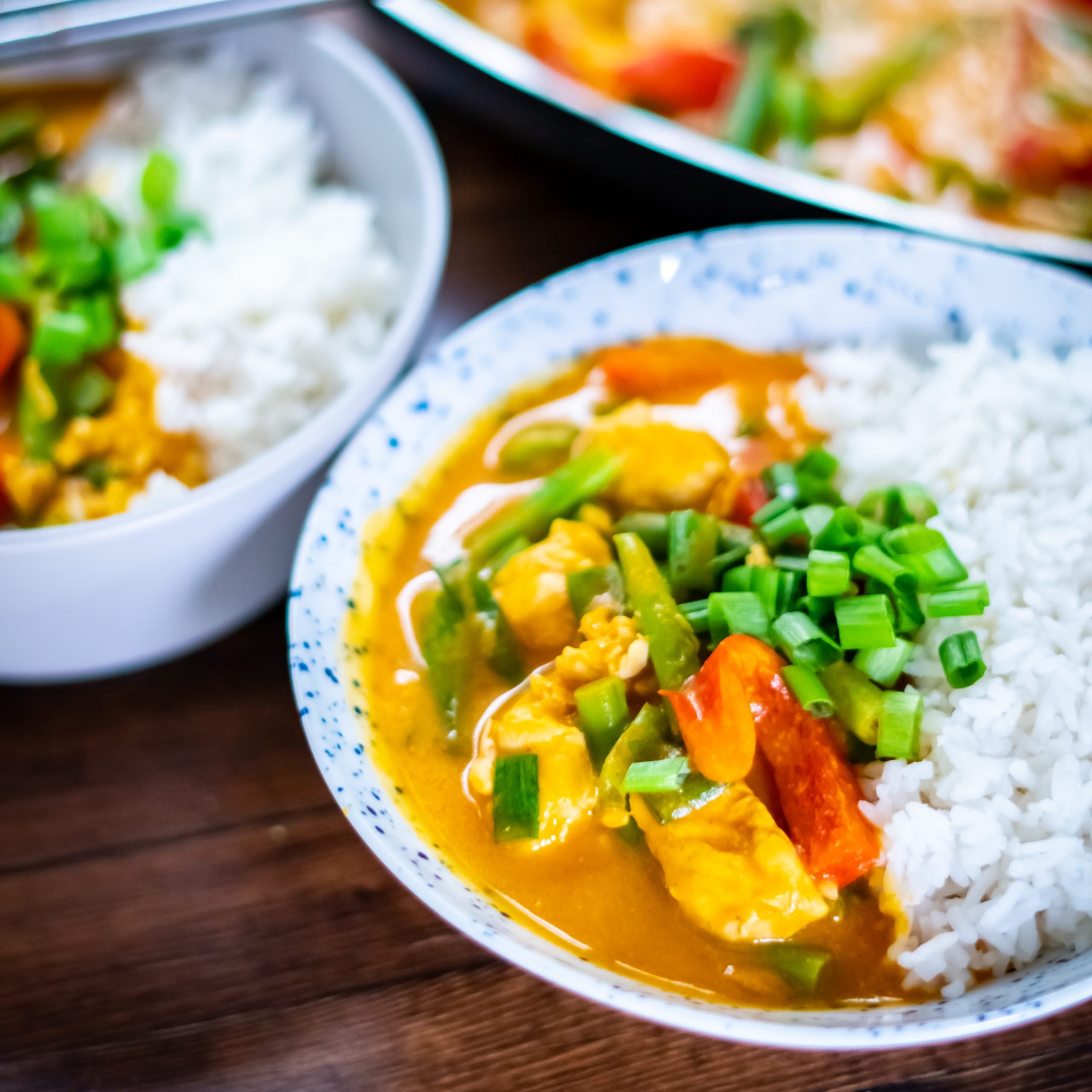 Side view of two serving bowls filled with white rice and pumpkin curry.