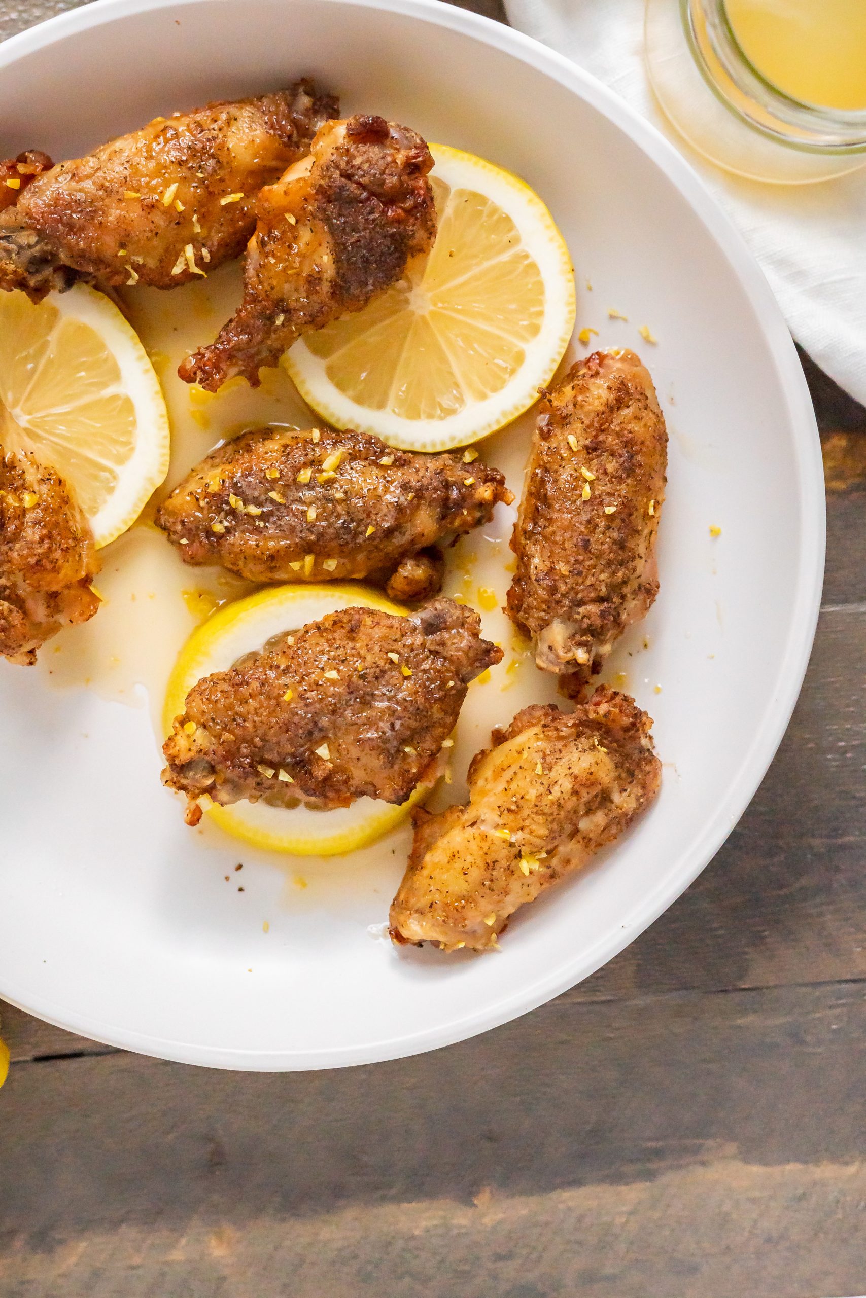 Overhead view of lemon pepper wings on a bed of lemon slices for serving.