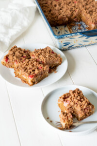 Three squares of rhubarb cake on a plate for serving.