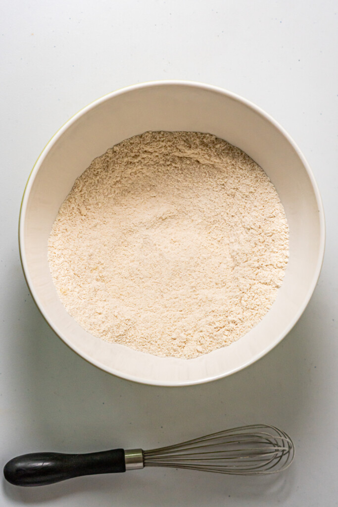 An overhead view of a bowl of dry ingredients mixed together with a whisk.