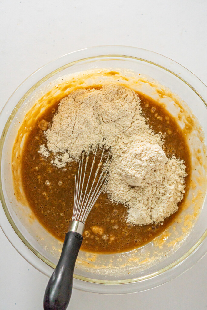 An overhead view of a bowl of wet ingredients with the first increment of dry ingredient mixture added.