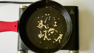 Minced garlic browning in olive oil in a cast iron skillet.