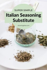 Side view of a jar of italian seasoning substitute with a small pile of each spice on a plate beside it.