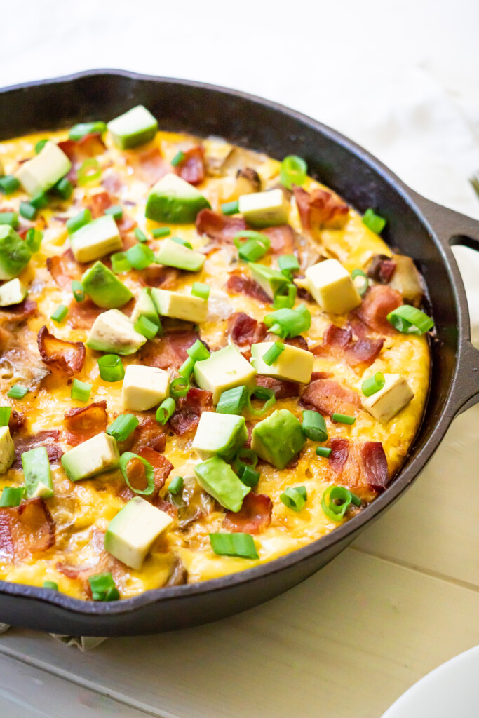 Side view of the Southwest Breakfast skillet in cast iron with bacon, avocado, and green onions on top!