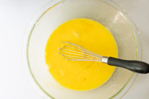 Overhead view of uncooked eggs whisked with milk.