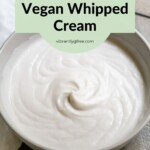 Side view of a just-whipped bowl of dairy-free whipped cream with whisk on the side.