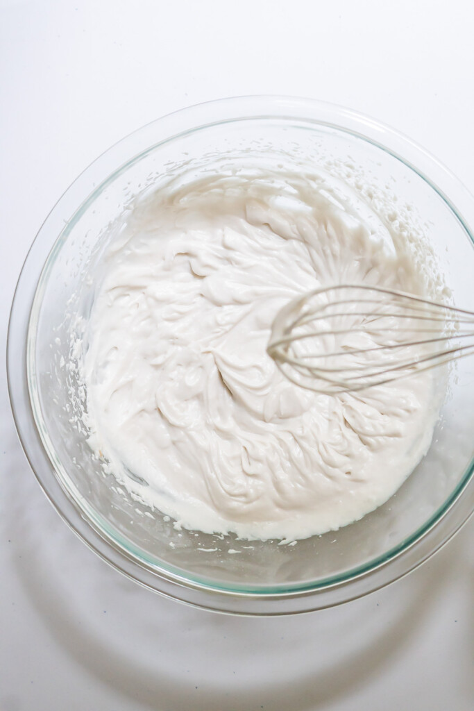 Overhead view of an electric whisk over a freshly made batch of dairy free whipped cream.