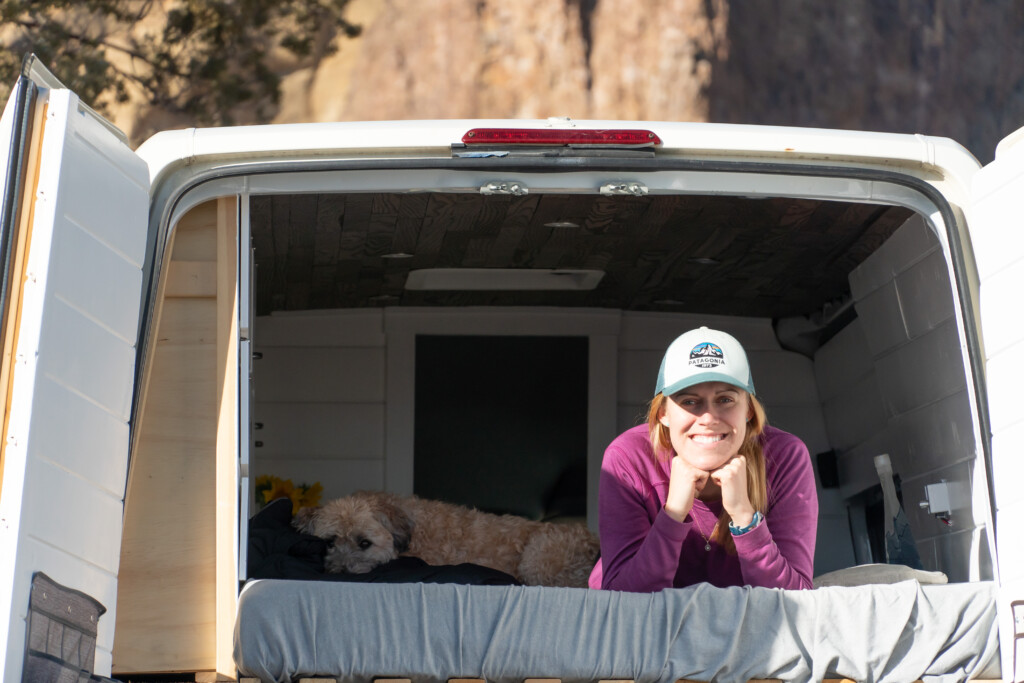 Jamie and Kaia lying on the camper van bed with Smith Rock in the background.