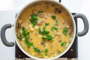 Overhead view of Dairy-Free Zuppa Toscana with all ingredients simmering in a dutch oven on the stove.