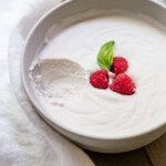 Side view of a bowl of coconut dairy-free whipped cream with a scoop removed to show the light and fluffy texture.