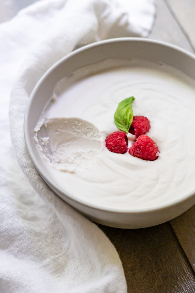 Side view of a bowl of coconut dairy-free whipped cream with a scoop removed to show the light and fluffy texture.