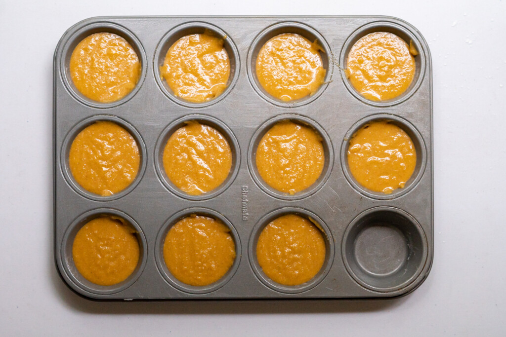 Overhead view of a 12 cup muffin pan with 11 cups filled with batter.