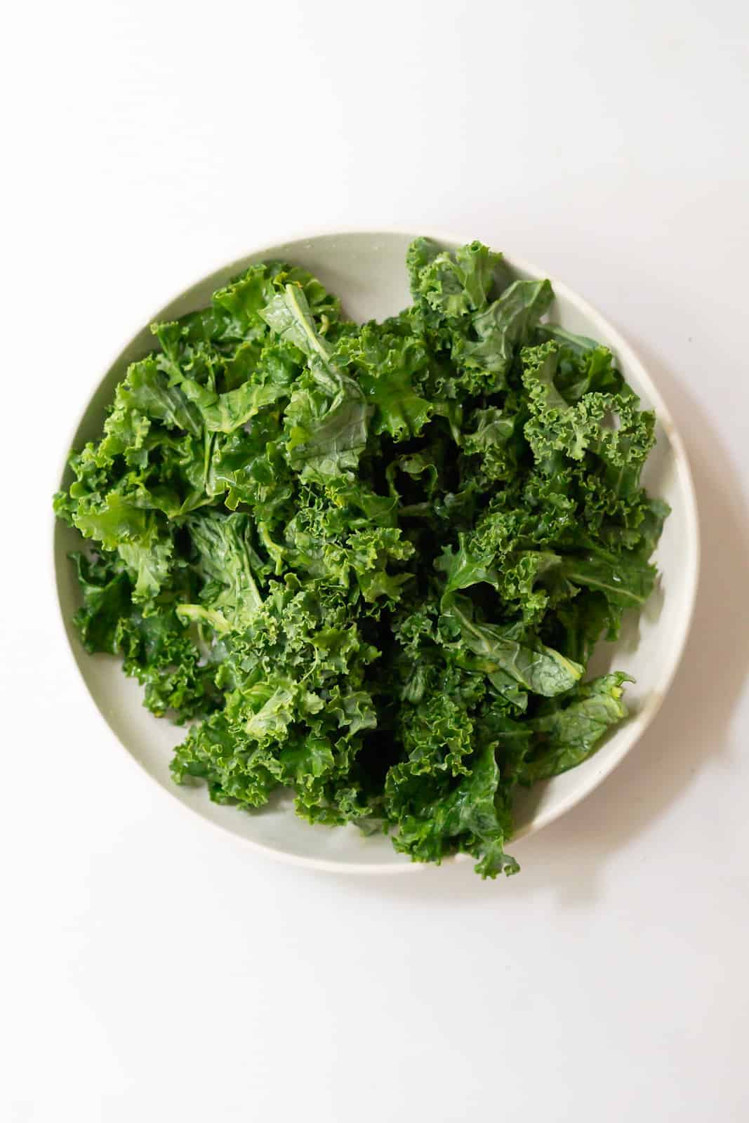 Overhead view of kale leaves torn into bite-sized pieces and massaged until tender.