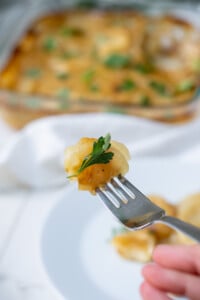 Side view of a tender bite of healthy dairy-free scalloped potatoes on a fork.