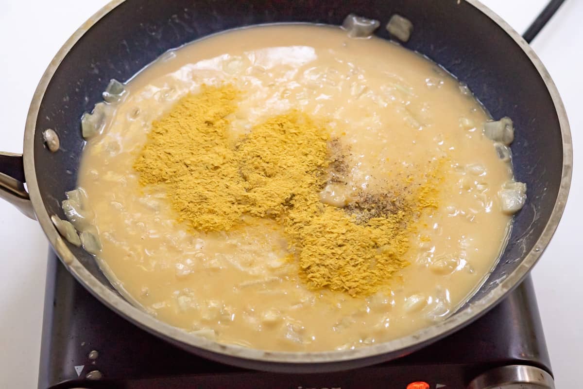 Side view of a thickened sauce with spices distributed on top, ready to be stirred in.