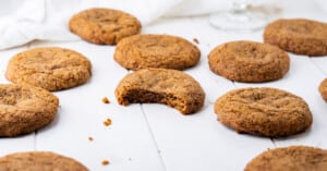 Side view of several paleo molasses cookies on a tabletop with a bite removed from one to show the soft and chewy texture!
