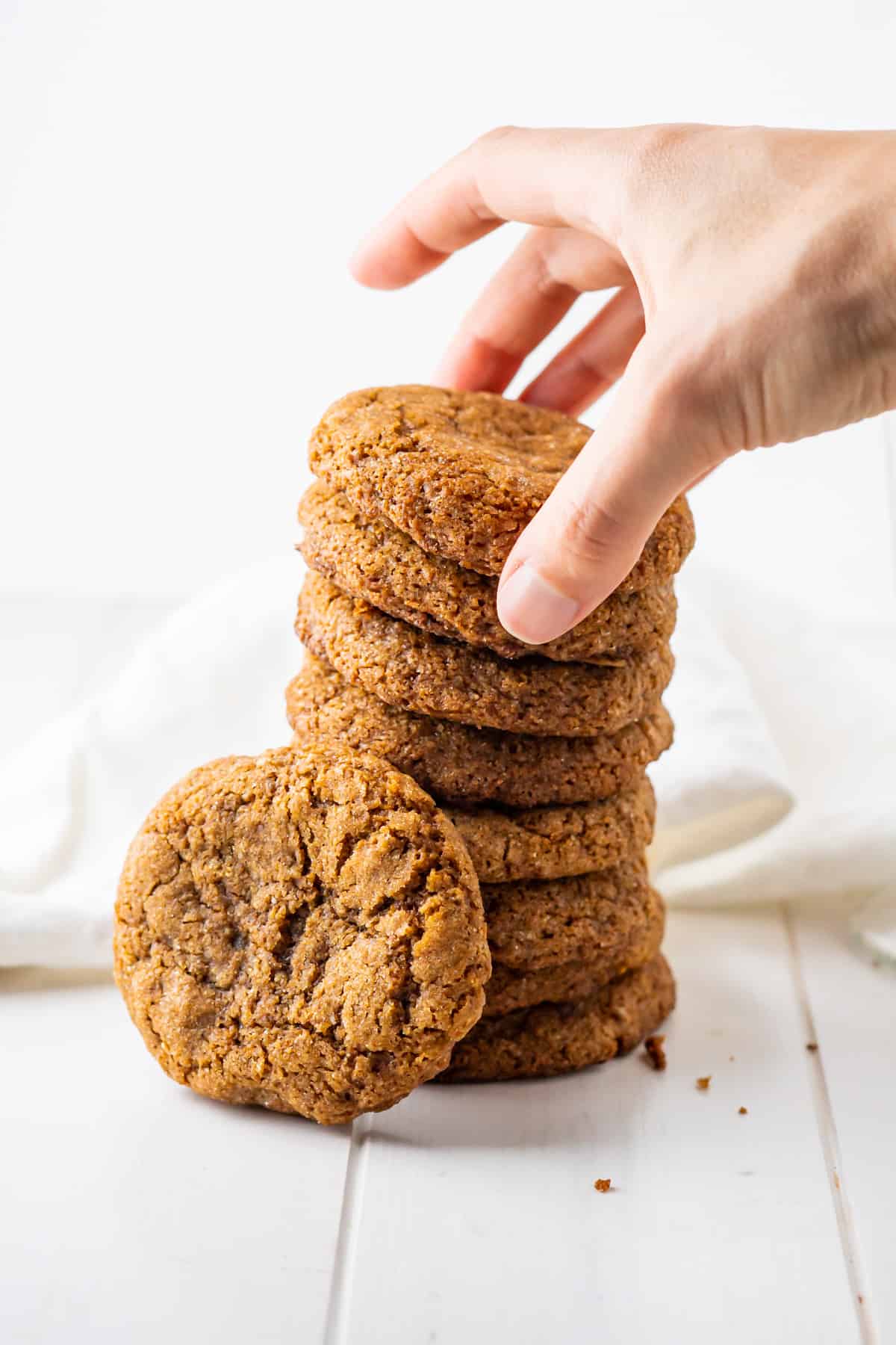A side view of a stack of paleo ginger molasses cookies with one laying in the front to show the crackly top and chewy texture!