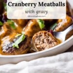Side view of Turkey Cranberry Meatballs with smooth buttery gravy and garnished with dried cranberries and chopped parsley. One meatball is cut in half to show the texture and variety.