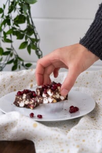 Side view of a hand taking a piece of Christmas Rocky Road candy from a serving plate!