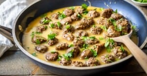 Side view of vegan swedish meatballs in a skillet with vegan gravy and parsley to garnish.