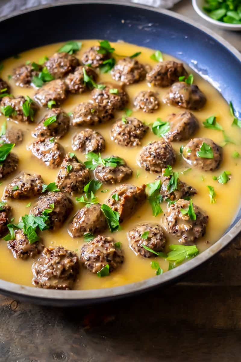 A skillet filled with vegan Swedish meatballs in a buttery vegan gravy.