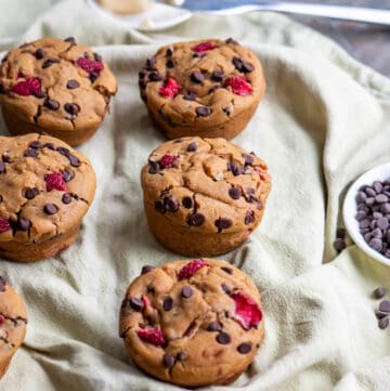 Six gluten free strawberry muffins with chocolate chips and butter on the side.