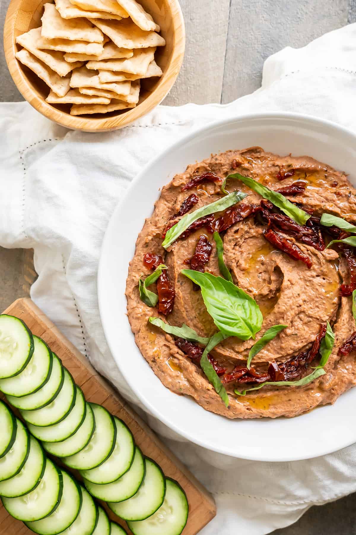 Creamy black bean hummus with a side of sliced cucumber and gluten-free crackers.