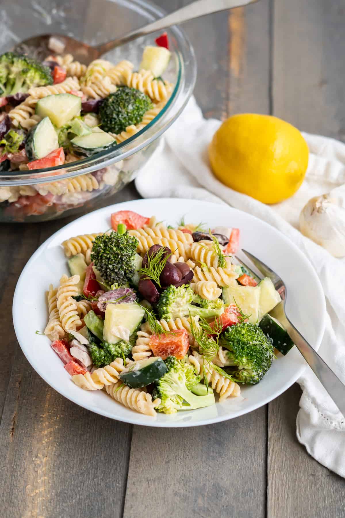 A plate of greek tahini pasta salad with fusilli noodles, cucumber, broccoli, fresh dill, and olives!