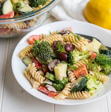 A plate of greek tahini pasta salad with fusilli noodles, fresh vegetables, and a creamy dressing.