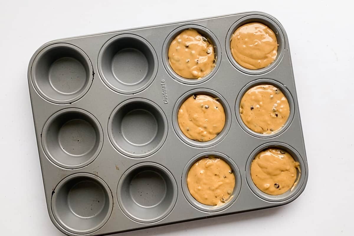 Six ups of a 12 cup muffin tin filled with gluten free chocolate chip muffin batter.