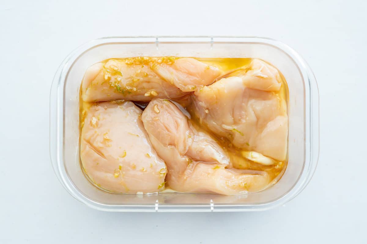 Chicken breasts marinading in a refrigerator-friendly container.