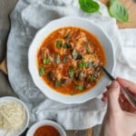Overhead view of a bowl of chicken cacciatore, without pasta, garnished with fresh basil leaves.