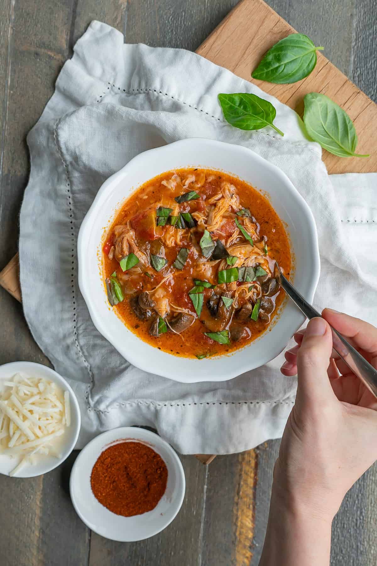 A bowl of instant pot chicken cacciatore garnished with fresh basil leaves.
