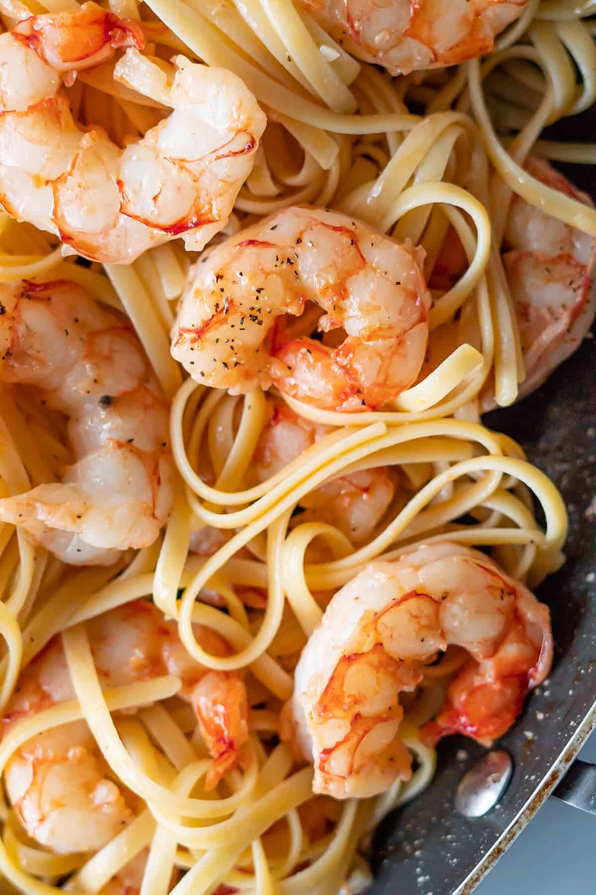 Close up of a pan of linguine pasta with these easy shrimp scampi mixed through.