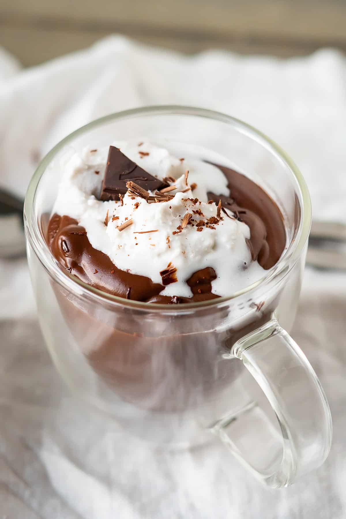 A clear glass mug of thick Italian hot chocolate with a super creamy texture.