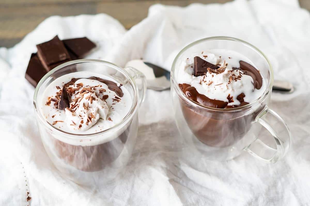 Two Italian Hot Chocolates in glass mugs and topped with whipped cream.