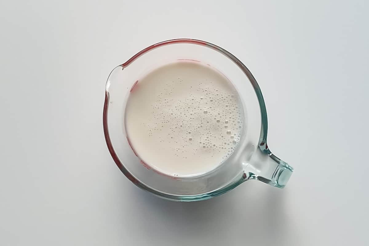 A liquid measuring cup filled with 1 cup of cold milk.