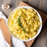 A serving bowl of Italian Olive Oil Mashed Potatoes garnished with rosemary.