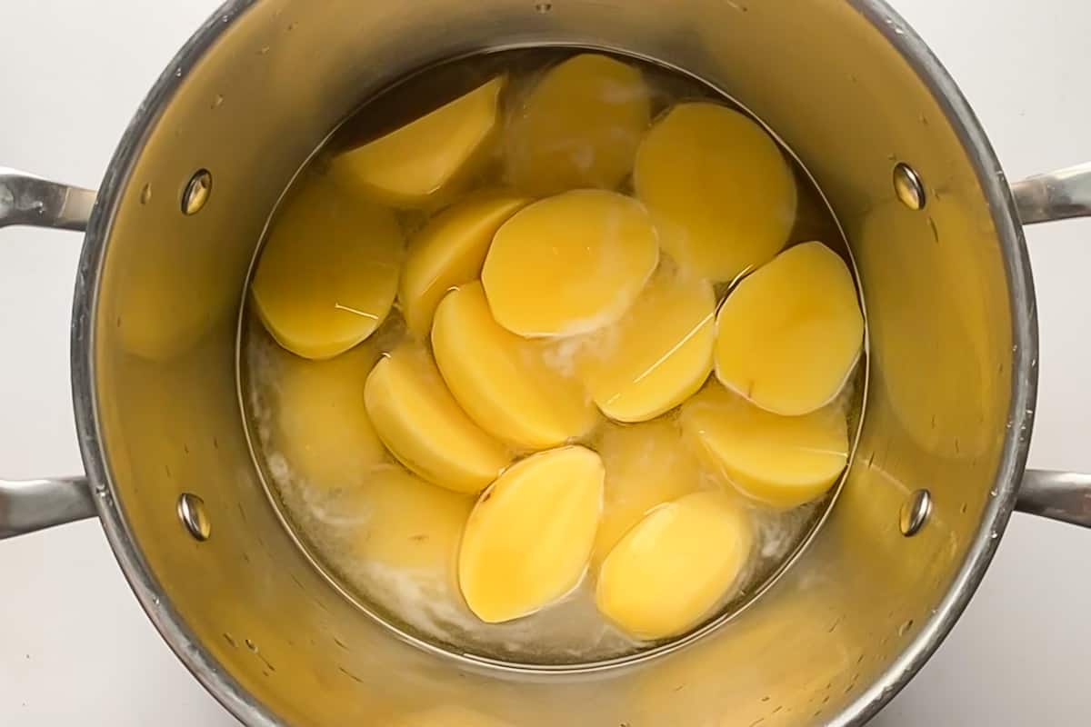 A large pot of gold potatoes peeled and halved and ready for boiling.