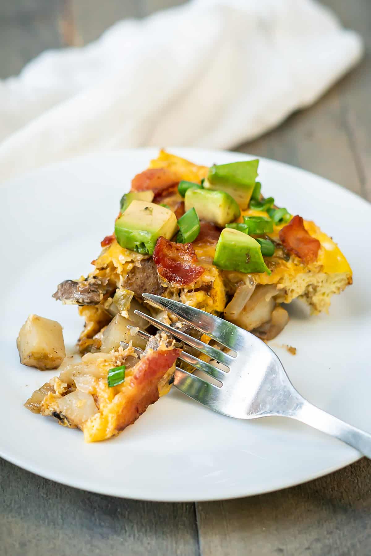 A slice of an egg and potato breakfast skillet to show the vegetable, egg, cheese, and bacon layers.