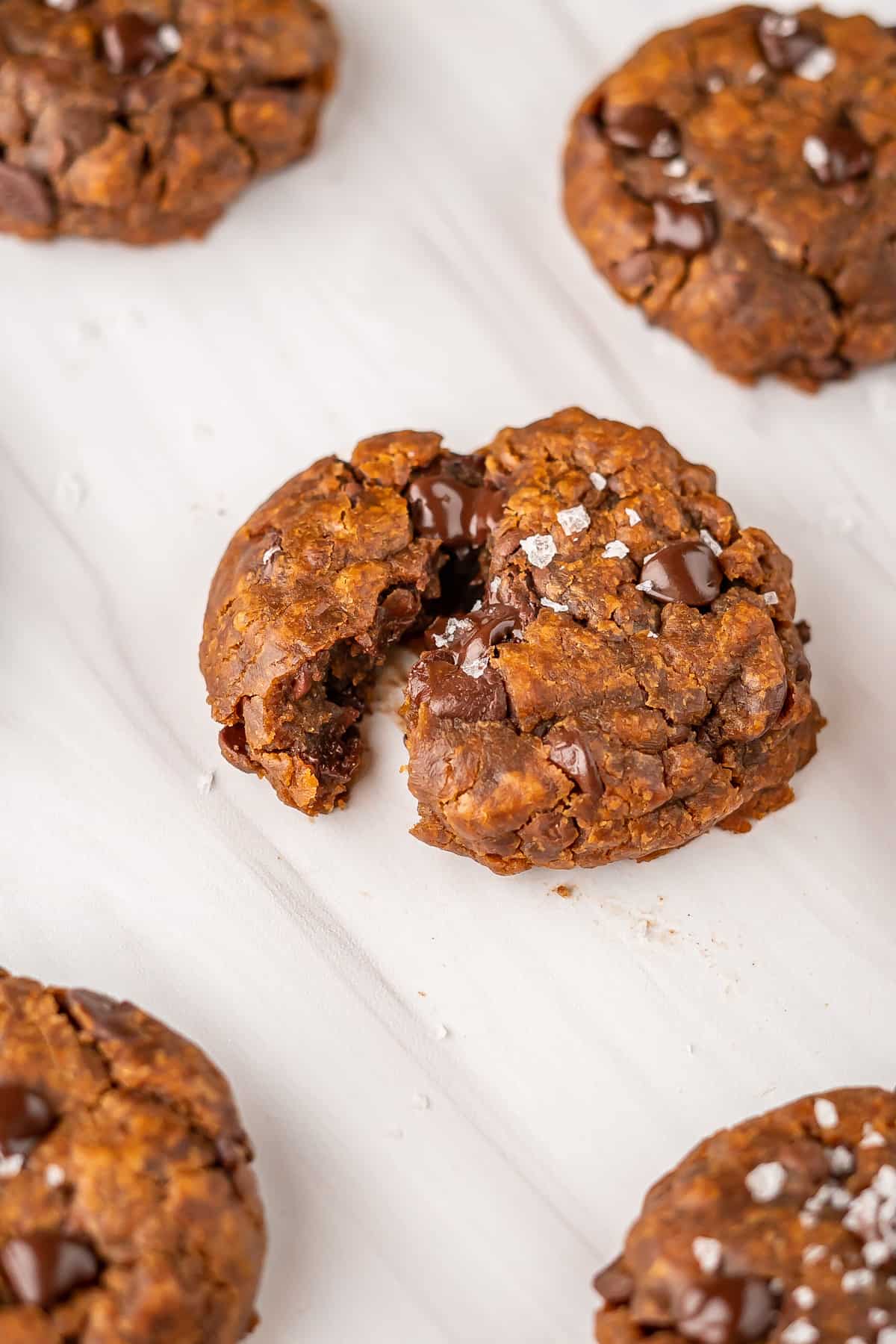 A coconut sugar chocolate chip cookie broken in half to show the chewy inner texture.