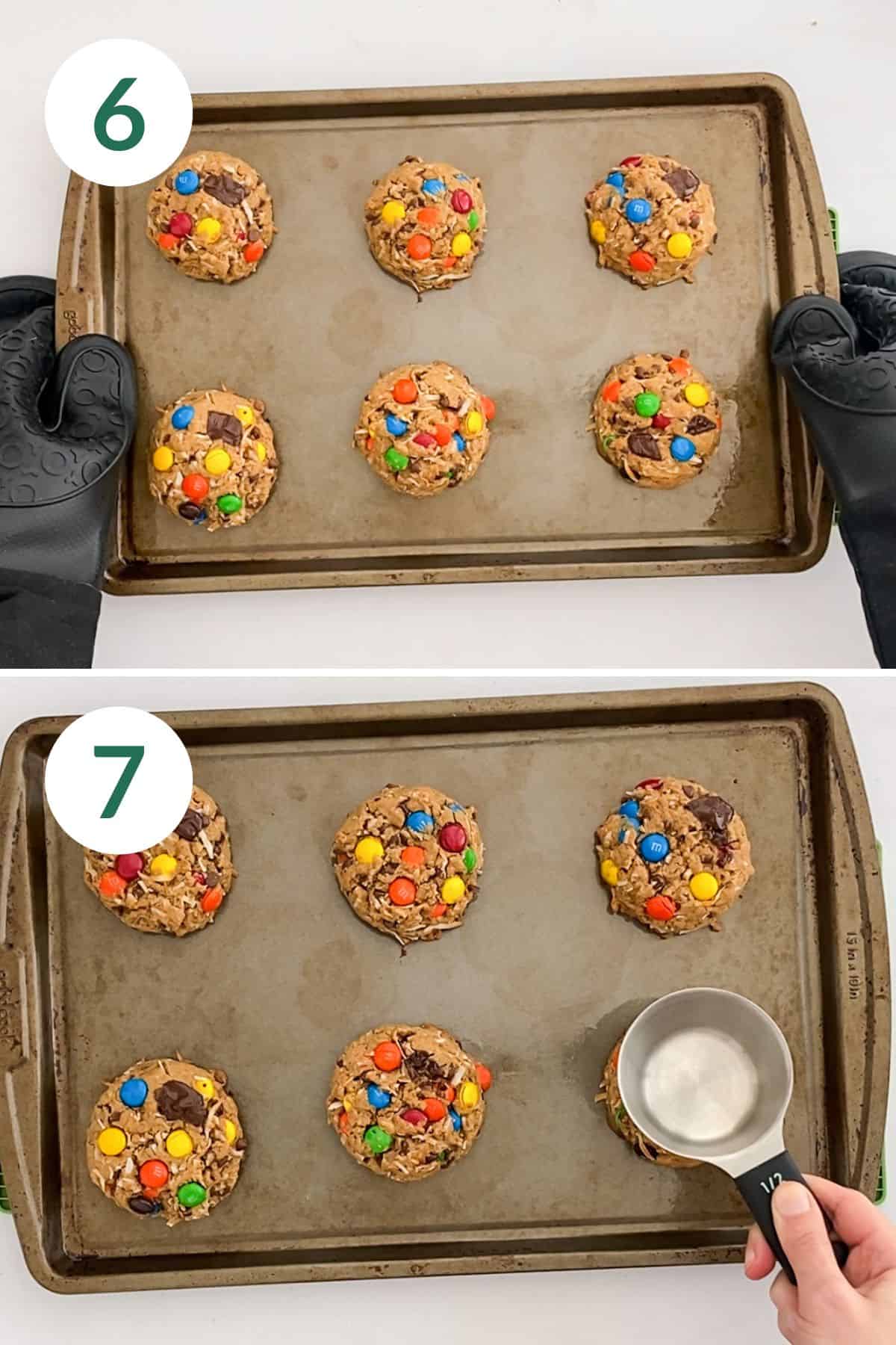 A baking sheet of freshly baked cookies and a hand pressing a cookie down with the back of a measuring cup.