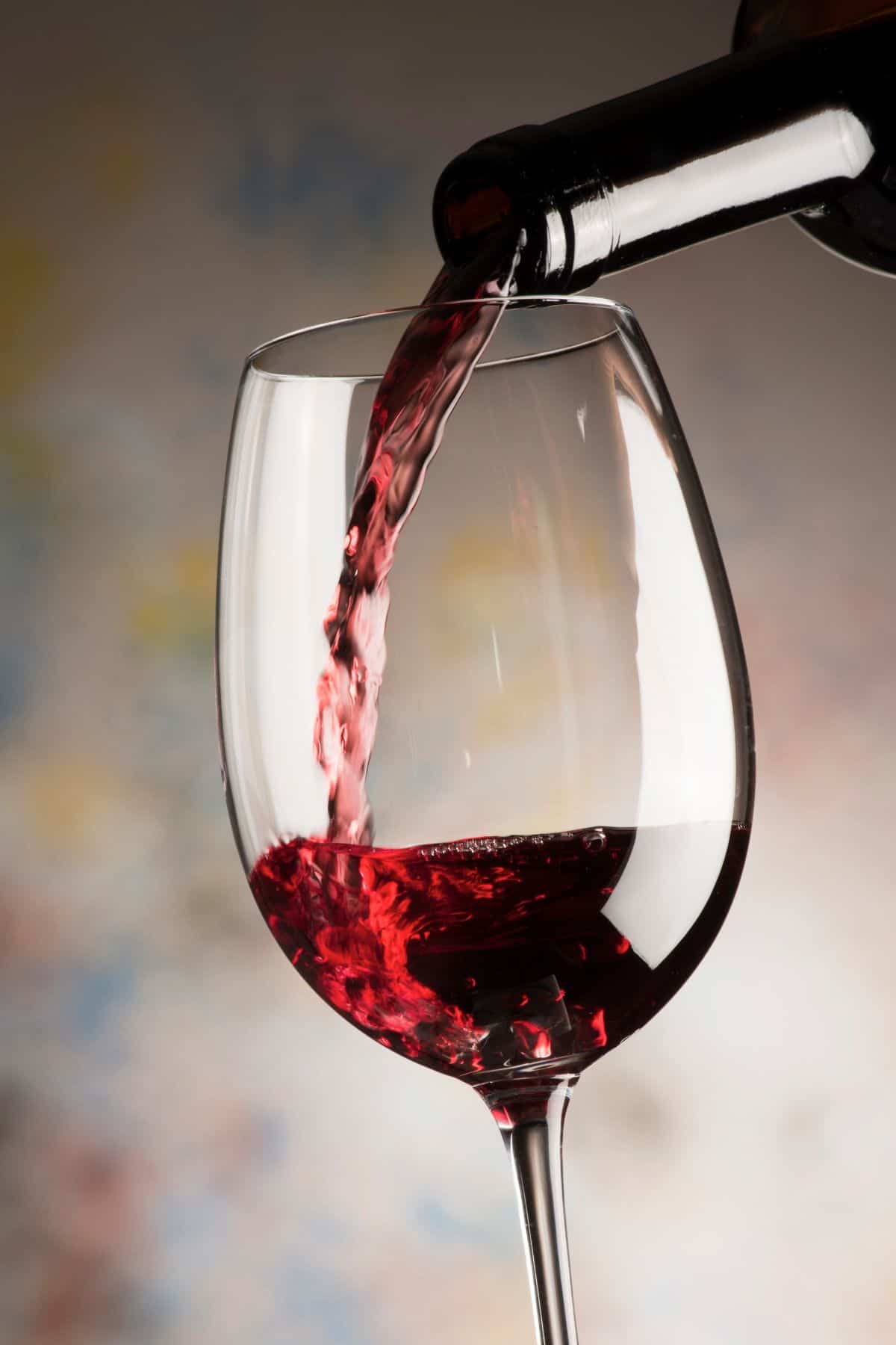 Red wine, which is naturally gluten-free, is poured into a large wine glass.