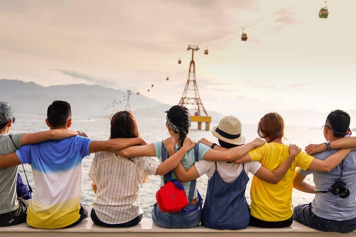 A supportive group of friends with arms around each other looking over the water.