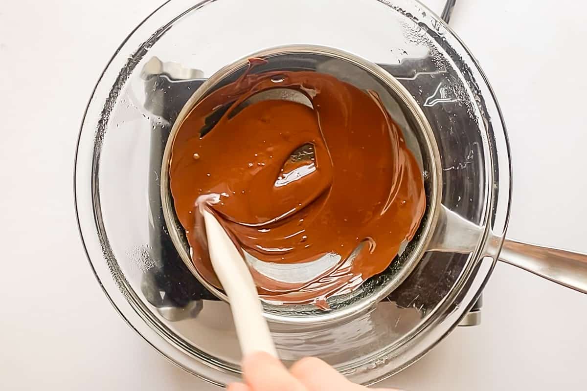 Melting chocolate in a glass bowl over a small pot of simmering water.