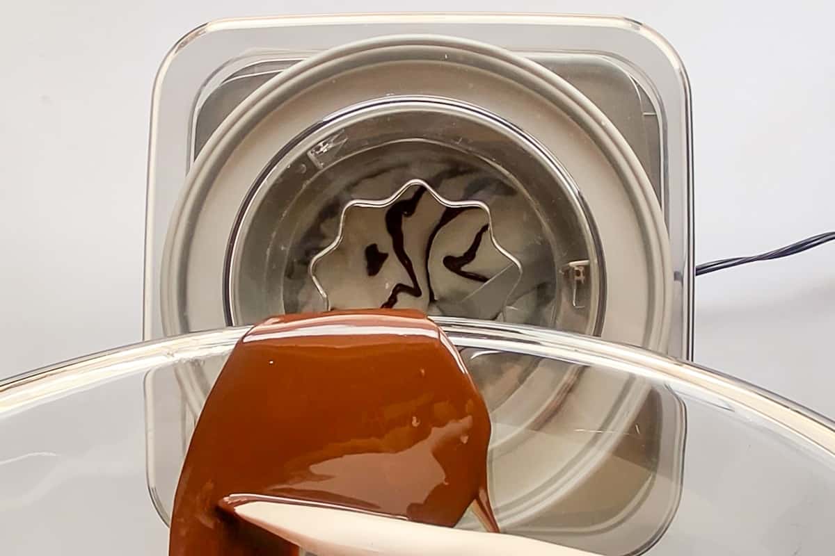 Pouring melted chocolate into an ice cream maker with soft-serve texture gelato mixture.