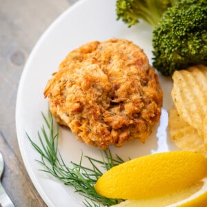 A crispy baked salmon cake with canned salmon served with broccoli, lemon, and fresh dill.